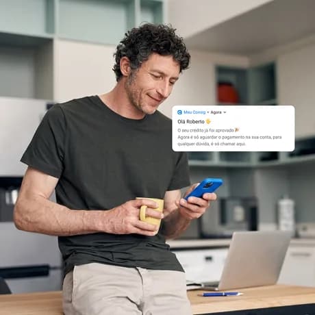 Homem olhando o celular com notificação de crédito aprovado no Meu Consig