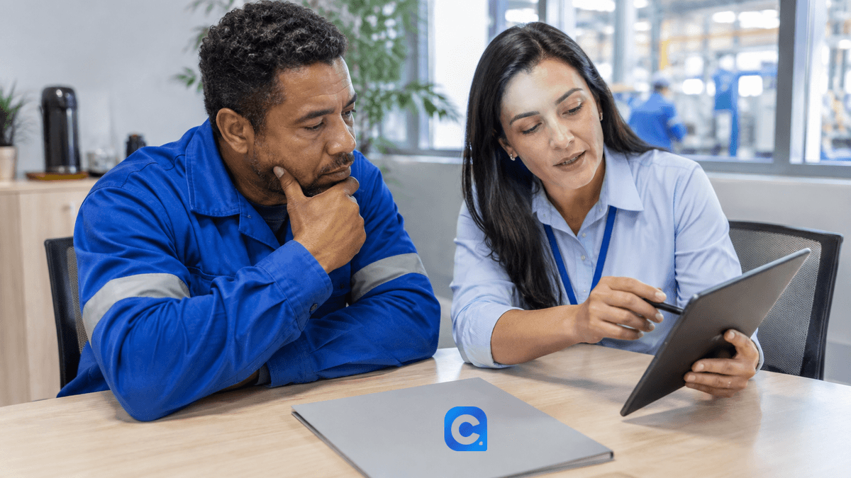 Trabalhador e assessora com roupas azuis conferem um tablet.